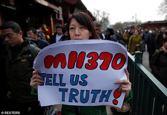 Catherine Gang, whose husband Li Zhi was on board Malaysia Airlines Flight MH370, holds a banner saying the passengers' families want the truth