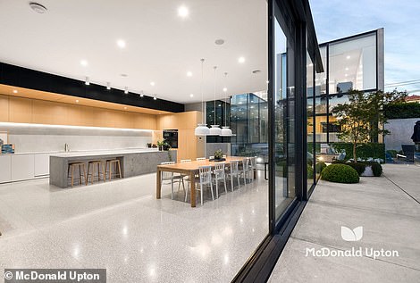 Through the entrance there is a long narrow walkway with double height ceilings that leads to the sun-drenched family room