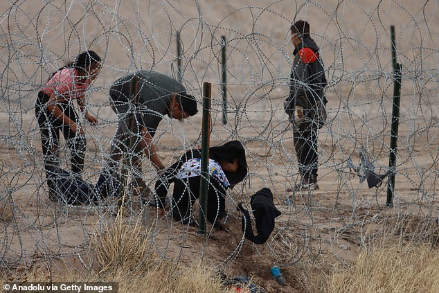 Since Biden took office, the total number of encounters at the southwestern land border has reached a staggering 7,298,486.  Pictured: Migrants cross the US-Mexico border under barbed wire on February 6, 2024