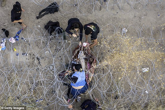 An aerial view of people passing through barbed wire after crossing the US-Mexico border into El Paso, Texas from Ciudad Juarez, Mexico on February 1, 2024