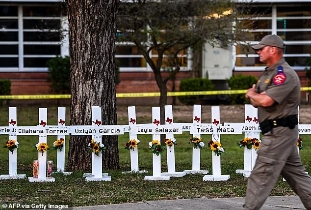 Police officers walk past a memorial for the victims of the Robb Elementary School shooting on May 26, 2022 in Uvalde, Texas