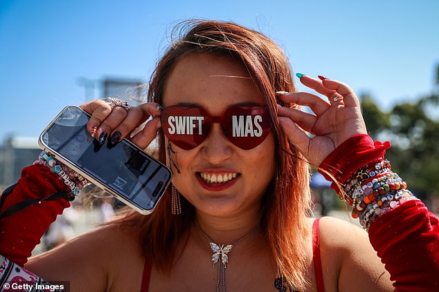 A Taylor Swift fan poses for a photo while wearing glasses that say Swiftmas