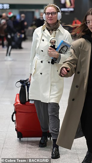 Pulling a suitcase next to her, the actress held the knitted doll close to her chest