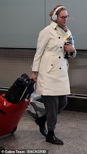 Uma wore a white double-breasted mac and casual gray trousers during her flight to Milan