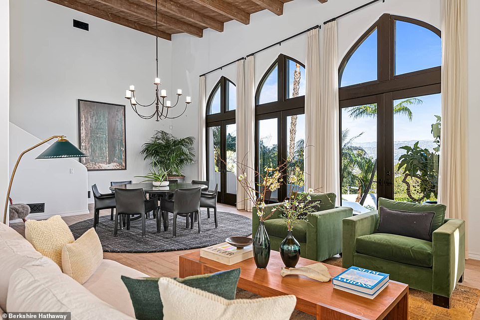 In the two-level living space, hardwood floors and high ceilings with wood beams create an intimate atmosphere