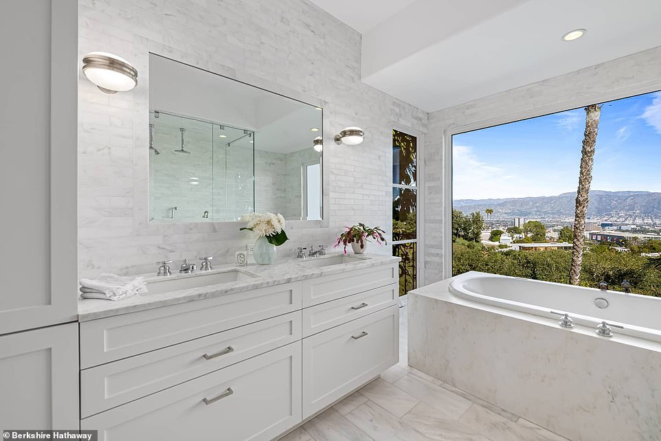 The bathroom features a luxurious bath complete with double sinks, a window view spa bath and a large glass shower