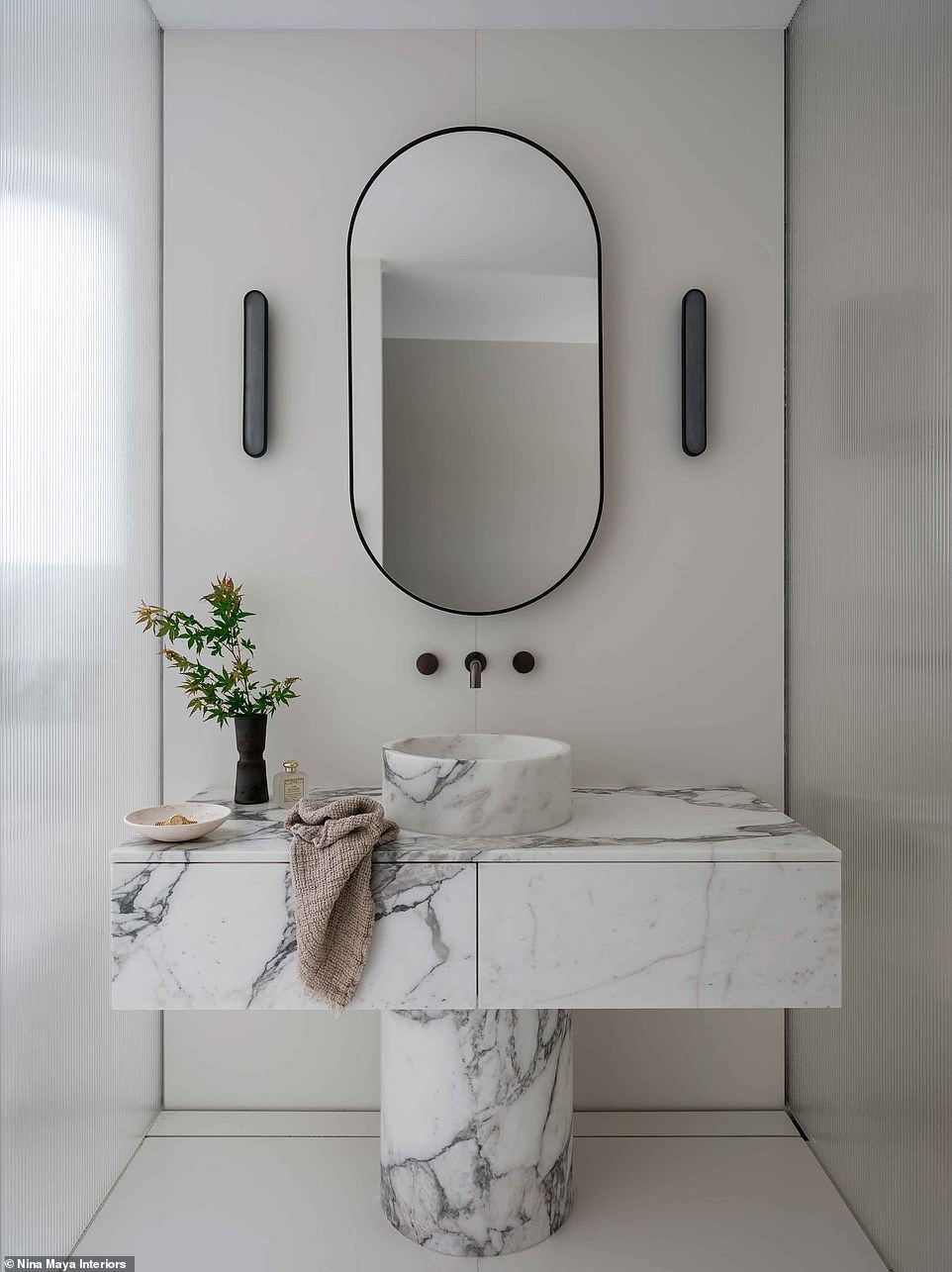 The sink was all marble with a round base and a round mirror above it.