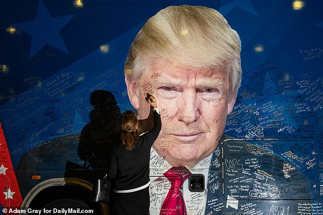 People write on a Trump-themed bus at the Conservative Political Action Conference, CPAC 2024, at the Gaylord National Resort & Convention Center, Maryland