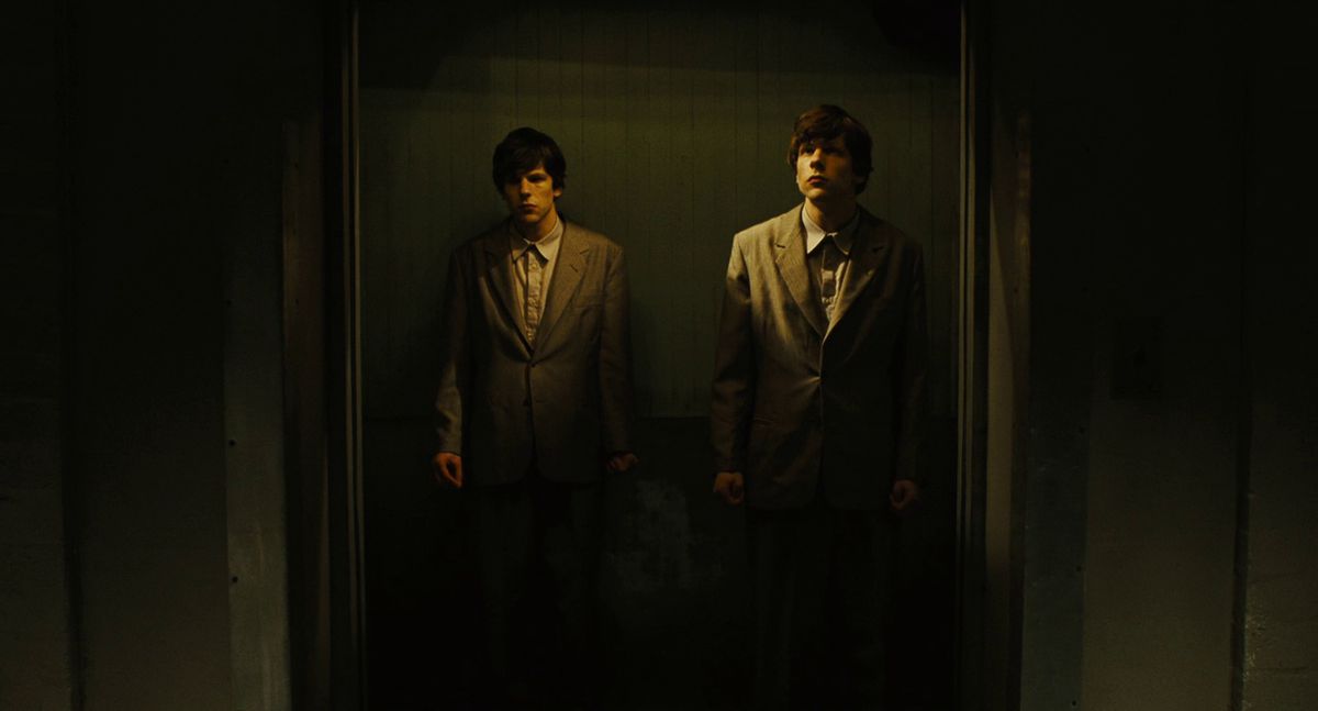 Two Jesses Eisenberg stand together in an elevator at The Double