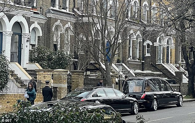 He paired a navy blue scarf with the smart coat and wore a white shirt and black tie in what appeared to be a funeral scene.