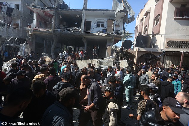 People gather in front of a building destroyed by the Rafah airstrike.  At least eight people were killed