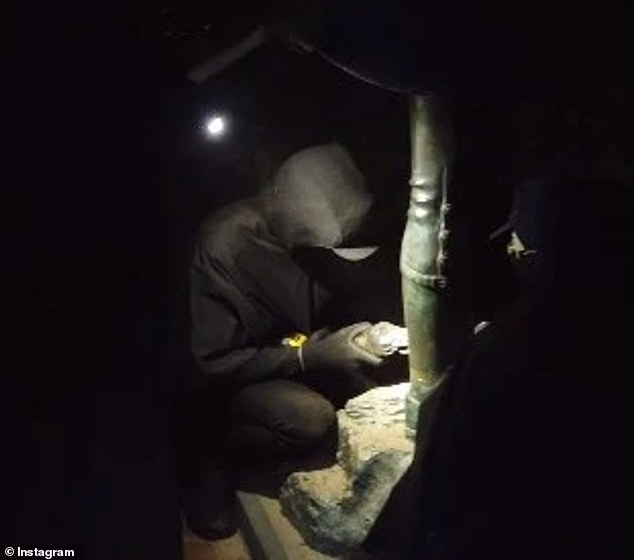 Images posted online appear to show a masked person dressed entirely in black using an angle grinder to saw the statue off the pedestal before it falls to the ground (photo)