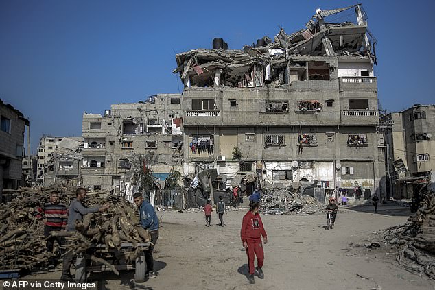 Palestinian men collect wood at a building destroyed during Israeli attacks in Beit Lahia in northern Gaza on February 26, 2024