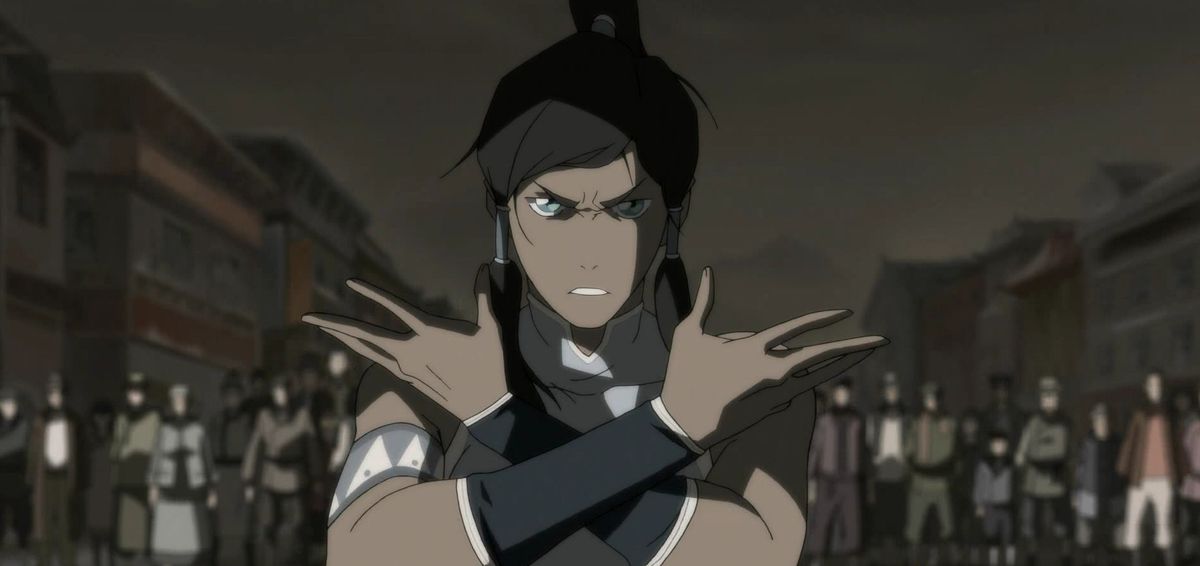 Main character Korra from The Legend of Korra stands in front of a crowd, arms folded, and stares into the camera