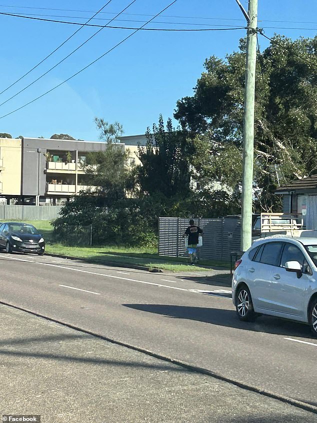 The man was seen walking along a footpath carrying the sign (pictured)