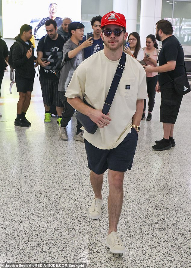 Nick, 31, cuts an understated casual figure in a light beige t-shirt, navy shorts and beige shoes