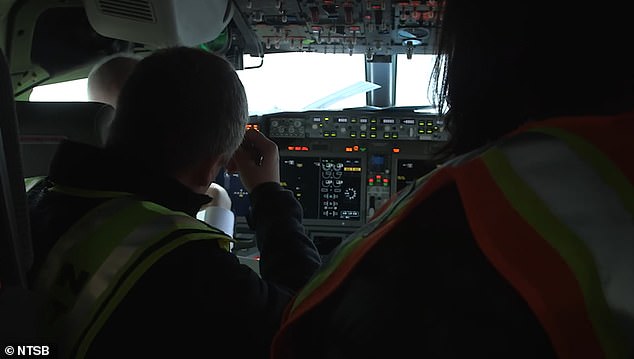 NTSB investigators sit in the cockpit as they investigate what caused a plug covering a spot left for an emergency door to tear off the plane while flying at 16,000 feet