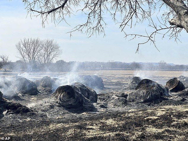 Smoke rises from smoldering hay bales outside the town of Canadian, Texas, on Wednesday