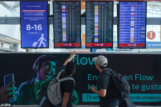 Passengers at Ministro Pistarini International Airport look at the flight information screen on Wednesday