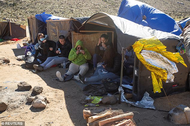 Migrants eat and rest in a makeshift camp as they wait to be processed by the Border Patrol