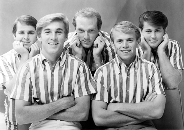 Wilson (far right) is considered one of the greatest songwriters of the 20th century for his innovative work with The Beach Boys (pictured in 1964).  In addition to composing many of their tunes, he sang lead and background vocals and played multiple instruments on their records;  (L – R) Carl Wilson, Dennis Wilson, Mike Love, Al Jardine and Brian Wilson