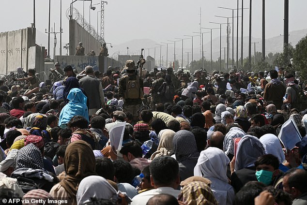 Afghans gather on the side of the road near the military part of the airport in Kabul, hoping to flee the country after the Taliban's military takeover of Afghanistan.