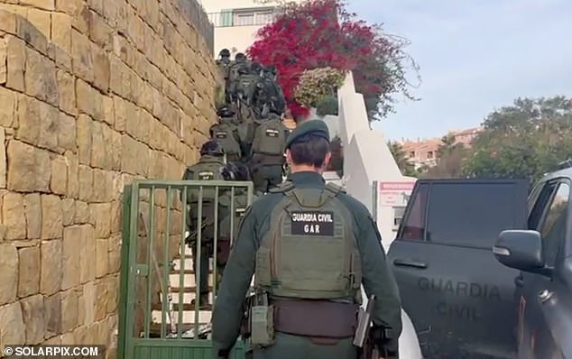 Officers carefully walk up the stairs during the raid.  A Guardia Civil spokesman said: 'Police carried out the raid after hearing about a drug drop on the seafront in La Linea'