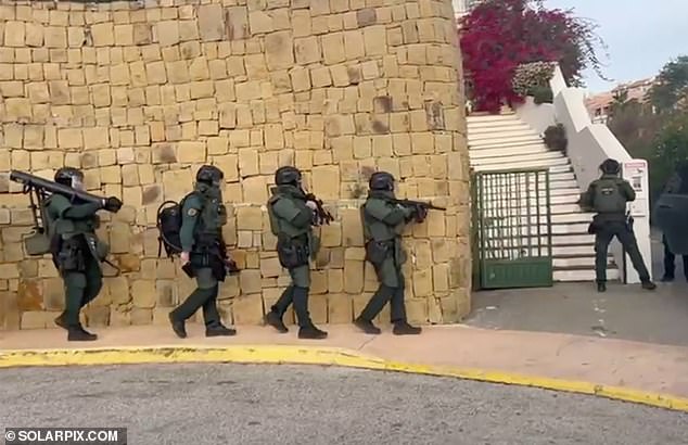 Detectives have described the seizure as one of the largest ever in Spain's southern Andalusia region.  You see a team of armed officers marching towards the house next to the wall before slowly ascending the stairs