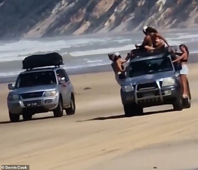 A silver Toyota Landcruiser was filmed driving at Rainbow Beach, Queensland, with five people hanging from the outside of the vehicle as another 4WD drove alongside