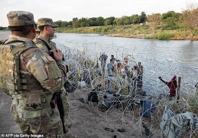 Migrants stand on the banks of the Rio Grande in Eagle Pass, Texas, where tens of thousands of migrants have crossed into the U.S. since December