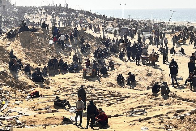 Palestinians wait for humanitarian aid today at a beach in Gaza City, Gaza Strip.  On the left you see a man praying