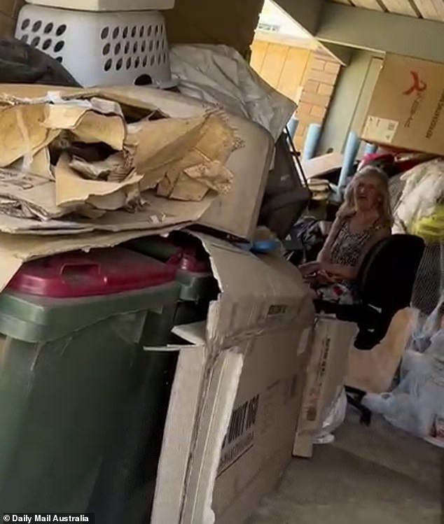 Maree sits among the rubbish strewn across her garage in the hours after her brother was found rotting inside