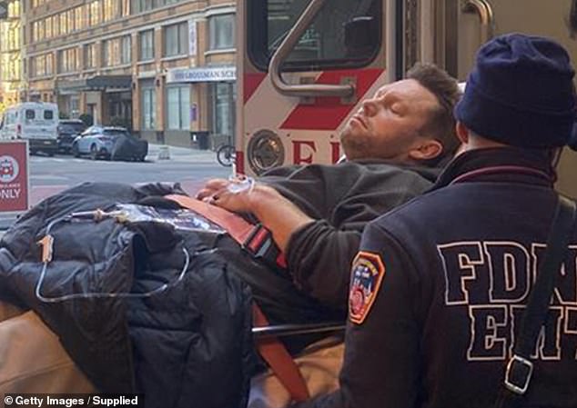 Sam Mitchell is loaded into an ambulance in New York after collapsing in front of his family at their hotel restaurant