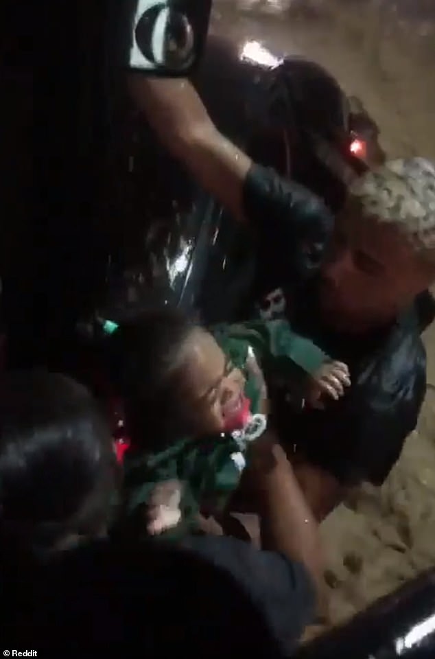 Marcos de Souza hands over one of the two one-year-old twin sisters he rescued with their mother on Wednesday evening after they were trapped in their family car on a flooded street in Rio de Janeiro