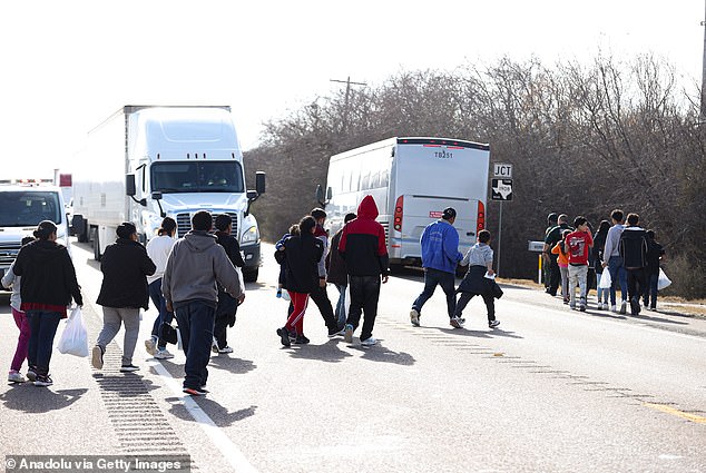 A group of migrants from different countries cross a road in Eagle Pass, Texas