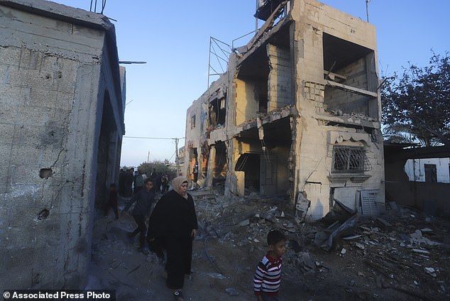 Palestinians walk past a residential building destroyed in an Israeli attack in Rafah, Gaza Strip, Sunday, February 11, 2024