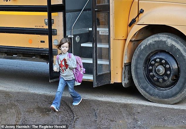 Little five-year-old Kolbie Hale with backpack in tow steps off the school bus after a grueling commute to work