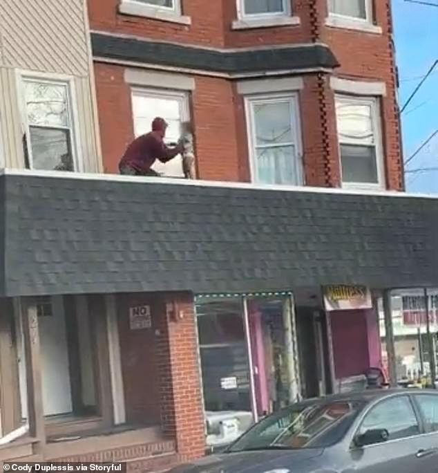 The man is seen grabbing the child who was walking alone on a roof on South Main Street in Woonsocket, Rhode Island, Tuesday morning.