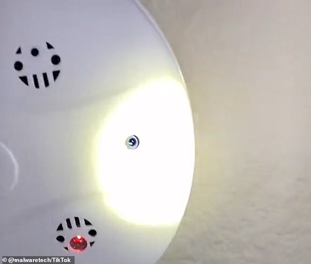 A powerful light shone on a smoke detector reveals the telltale glint of a lens placed in a hole