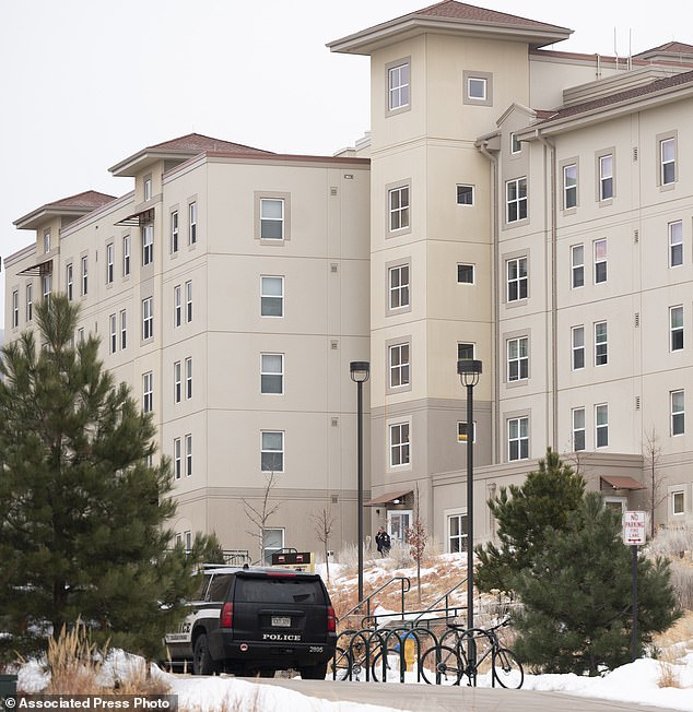 A police officer stands outside a Village at Alpine Valley residence hall on Friday as police investigate a shooting on the campus of the University of Colorado-Colorado Springs