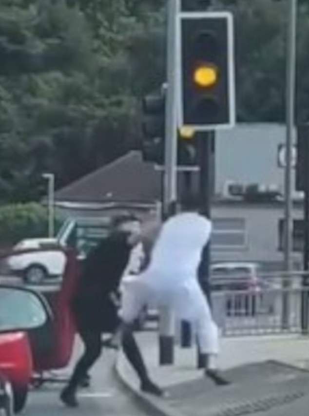 Horns are heard as the driver throws three punches with his right hand before the cyclist manages to return to a standing base