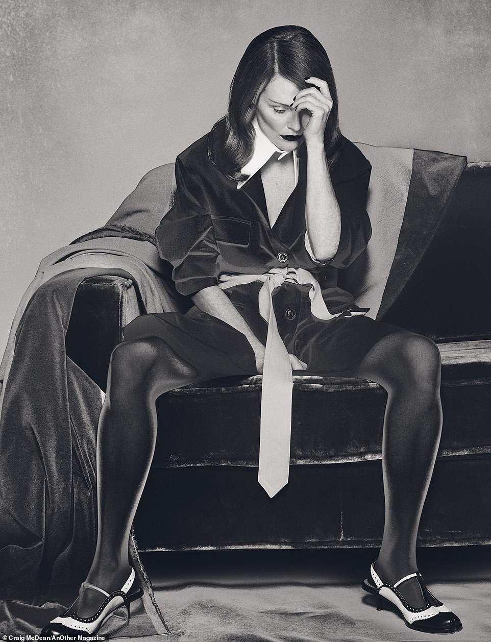 In another photo, taken by photographer Craig McDean and styled by Katie Shillingford, Julianne sits on a couch and looks dejectedly into her hand while wearing a velvet blazer with a large, pointed white collar and a men's tie for a belt from Maison Margiela