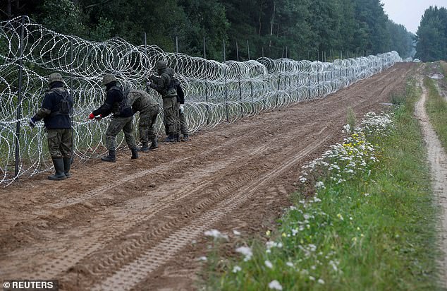 Polish soldiers are seen building a fence on the border between Poland and Belarus near the village of Nomiki, Poland, August 26, 2021