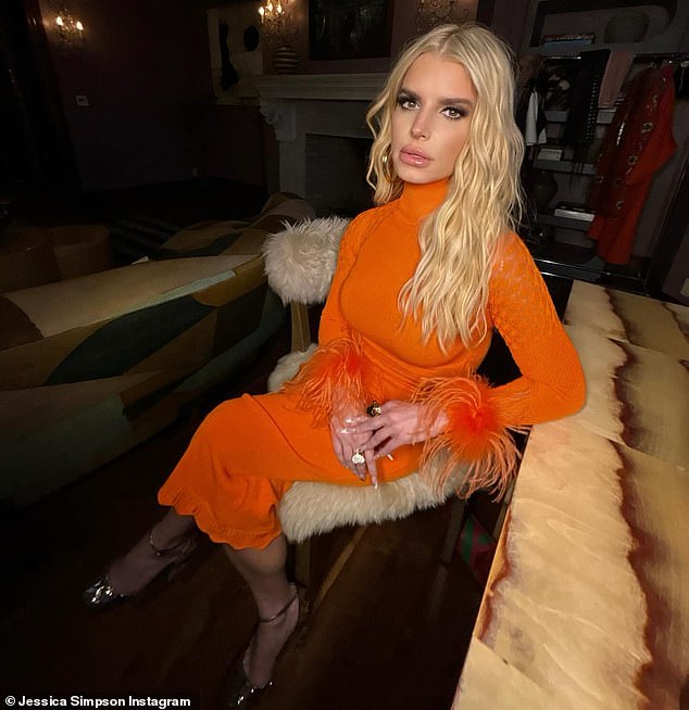 The 43-year-old singer turned designer modeled an orange dress with long sleeves and feather cuffs.  