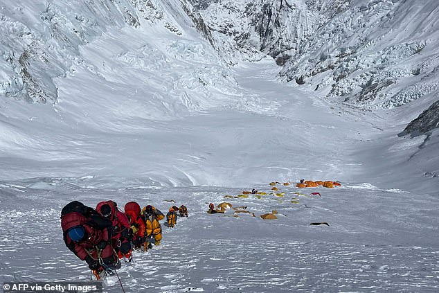 A group of mountain climbers climbing a slope during their climb to the summit of Mount Everest in 2021