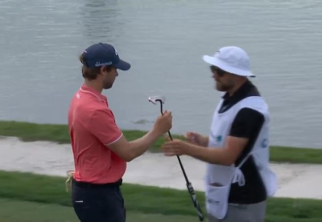 Detry hands his putter to his caddy after hitting eight shots on the sixth hole