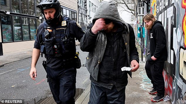 The measure makes possession of small amounts of drugs such as heroin or methamphetamine a crime, punishable by up to six months in prison (photo: police officer David Baer pulls a man who was caught smoking fentanyl)