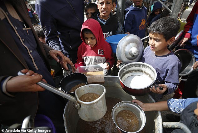 Palestinians queue for hours to receive food distributed by charity organizations, in Deir Balah, Gaza on March 1, 2024