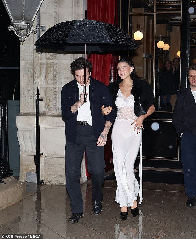 Brooklyn followed in his father's footsteps and also held an umbrella for his wife as they made their way through the downpour