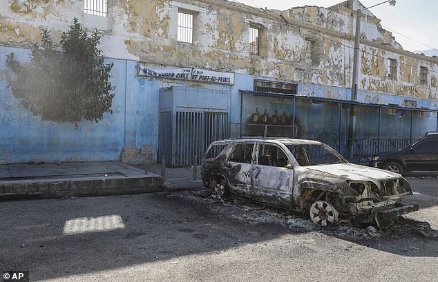 Pictured: A burnt-out car outside the city's National Penitentiary, where hundreds of inmates are believed to have escaped